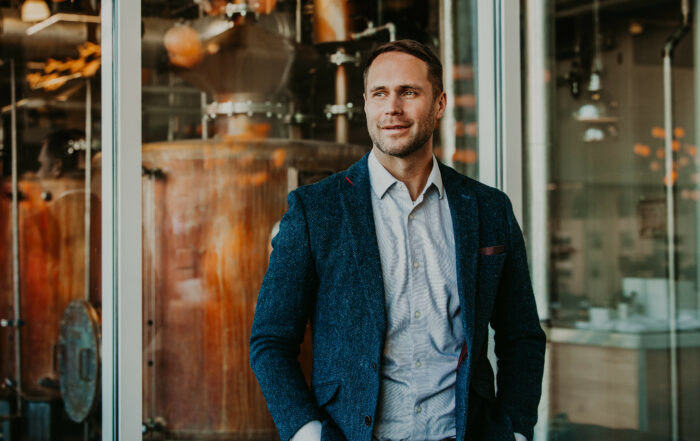 Dan Callaway, Master Blender at Lofted Spirits, standing in a distillery in a blue blazer